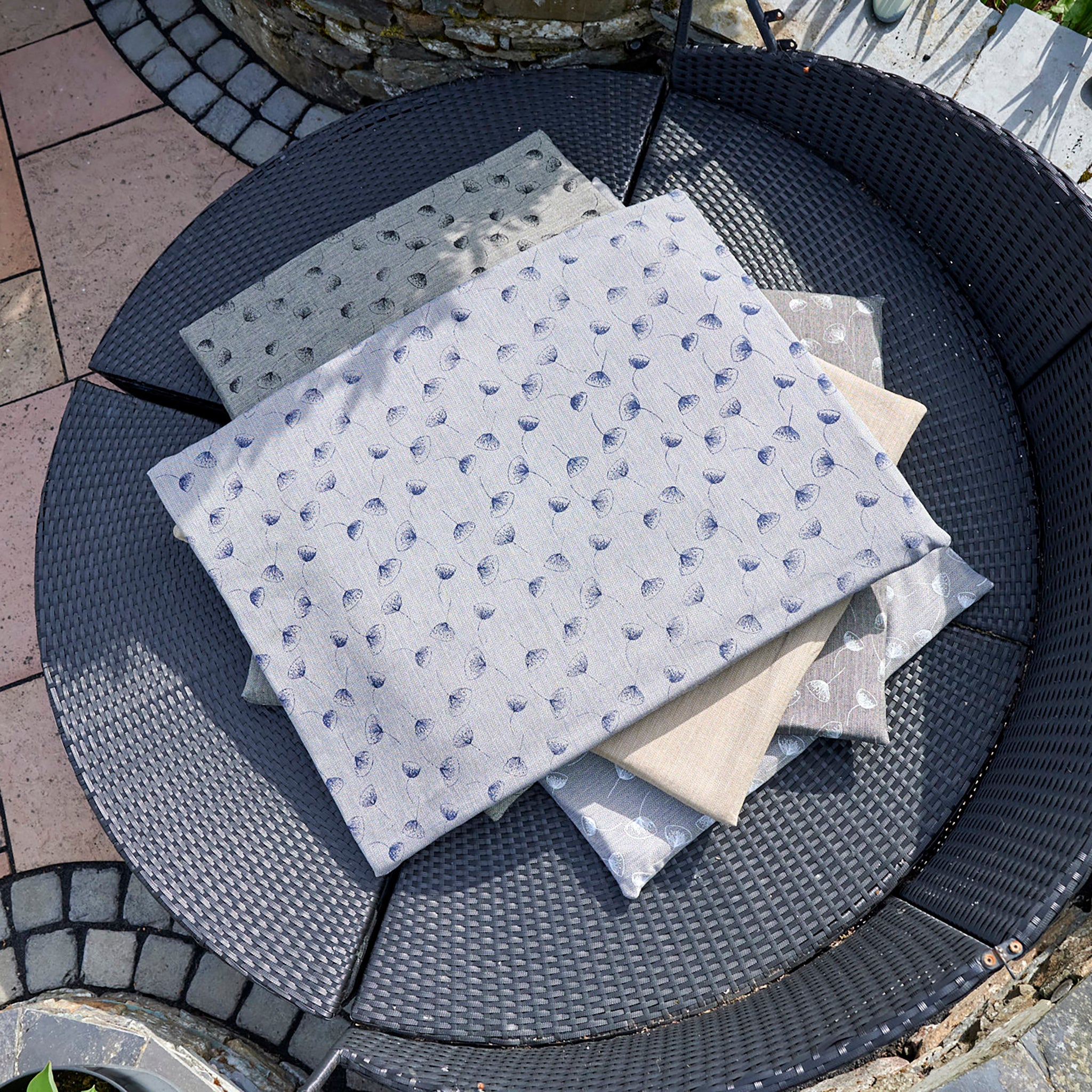 Chimney Sheep Luxury Wool Filled dog beds, placed neatly in a pile. The blue with dark blue flowers pattern is ontop, with the olive and grey patterns sitting beneath