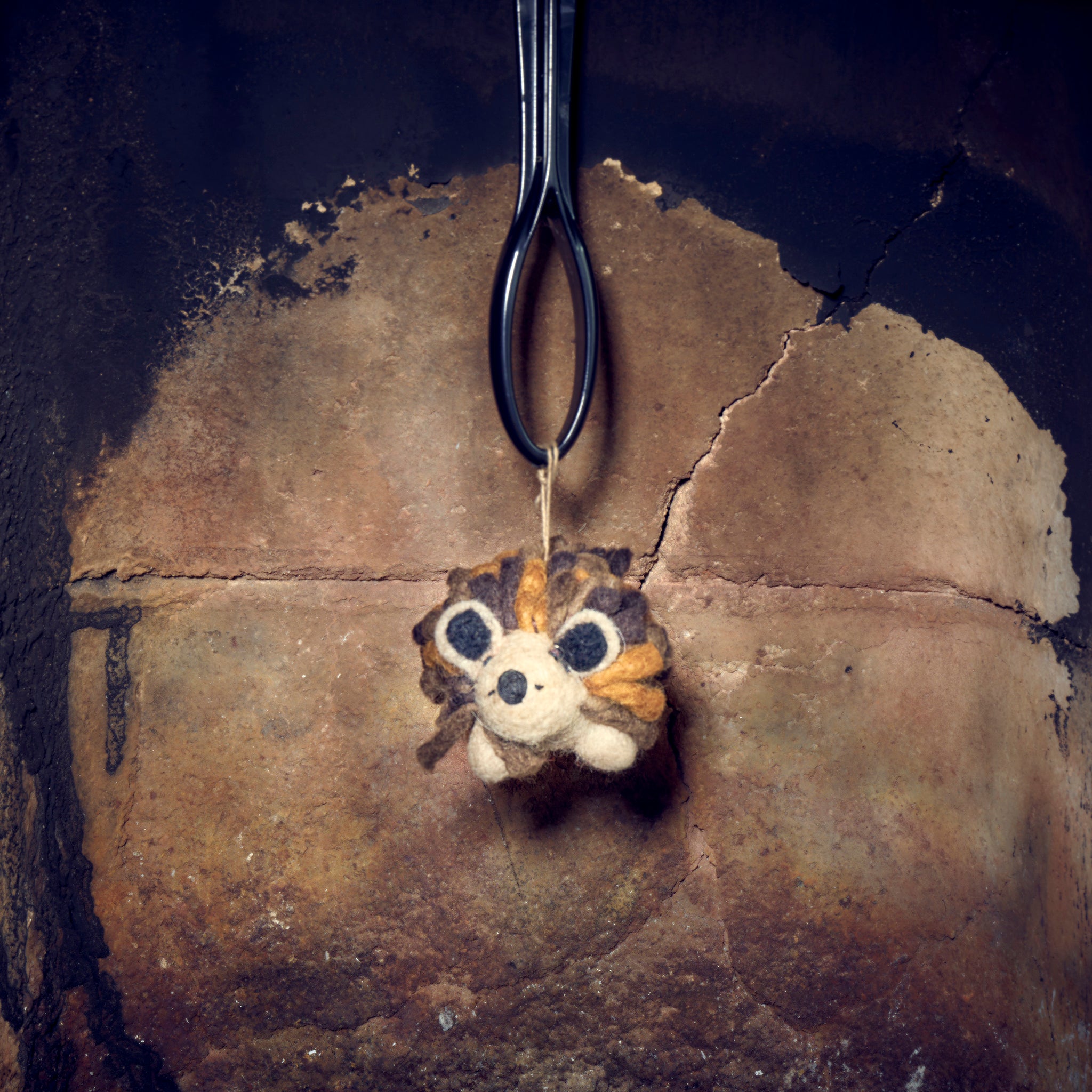 Woolly felted hedgehog in fireplace showing the face.