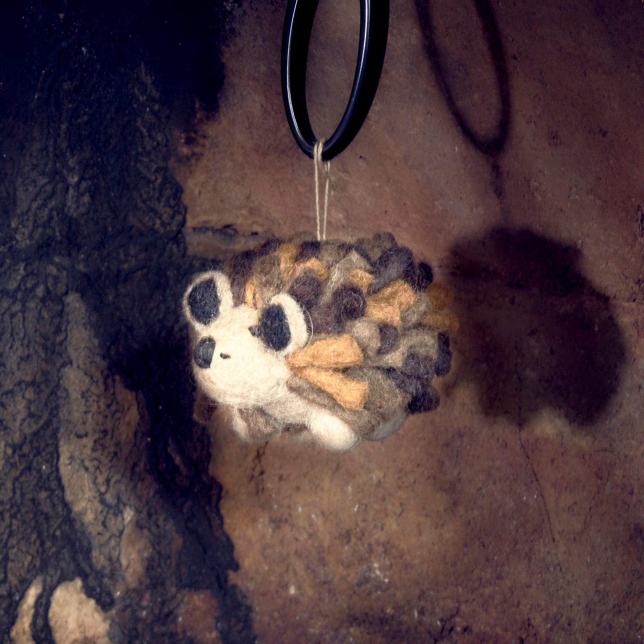 Woolly felted hedgehog hanging  in fireplace, side view.