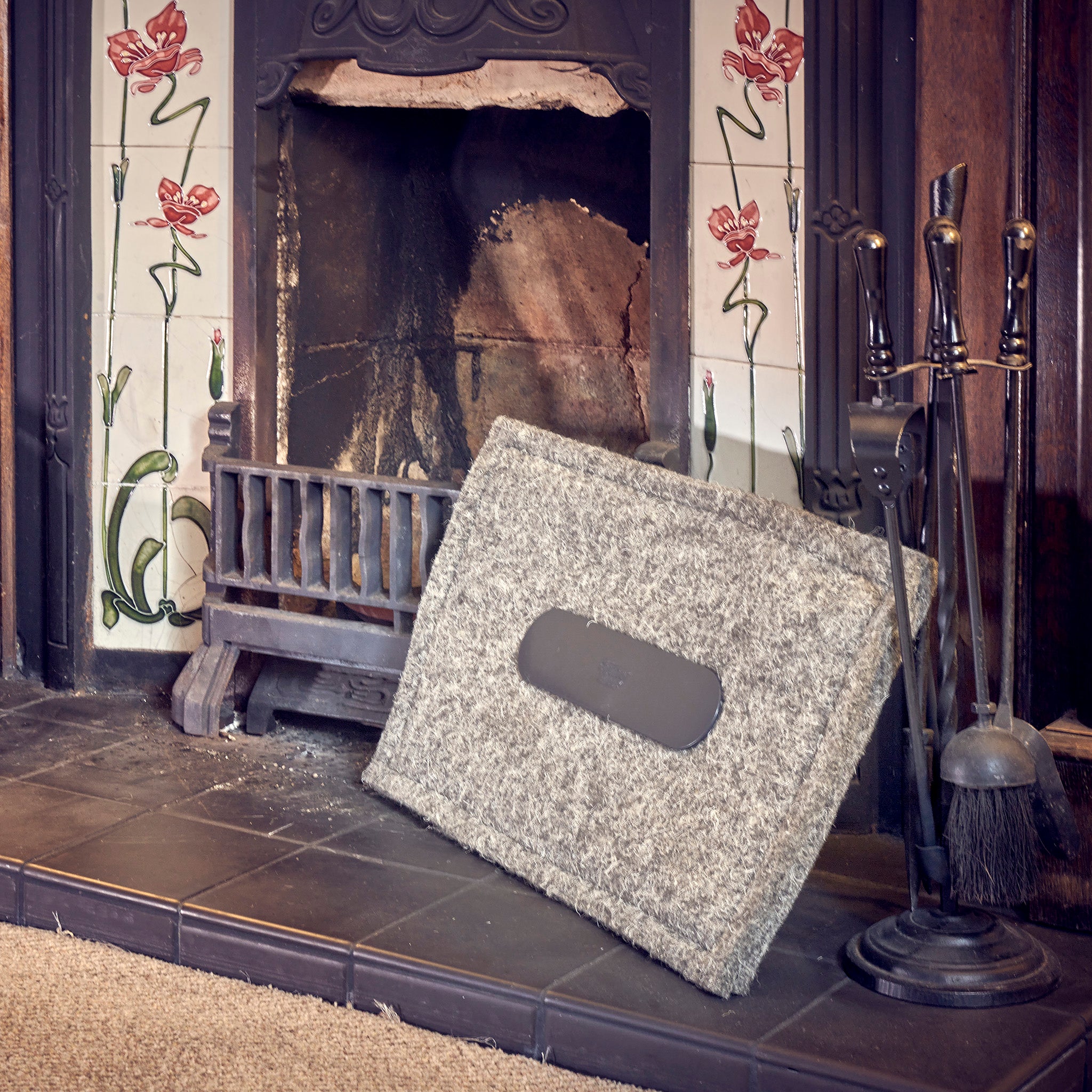 A removable Chimney Sheep chimney draught excluder leaning against an open fireplace.