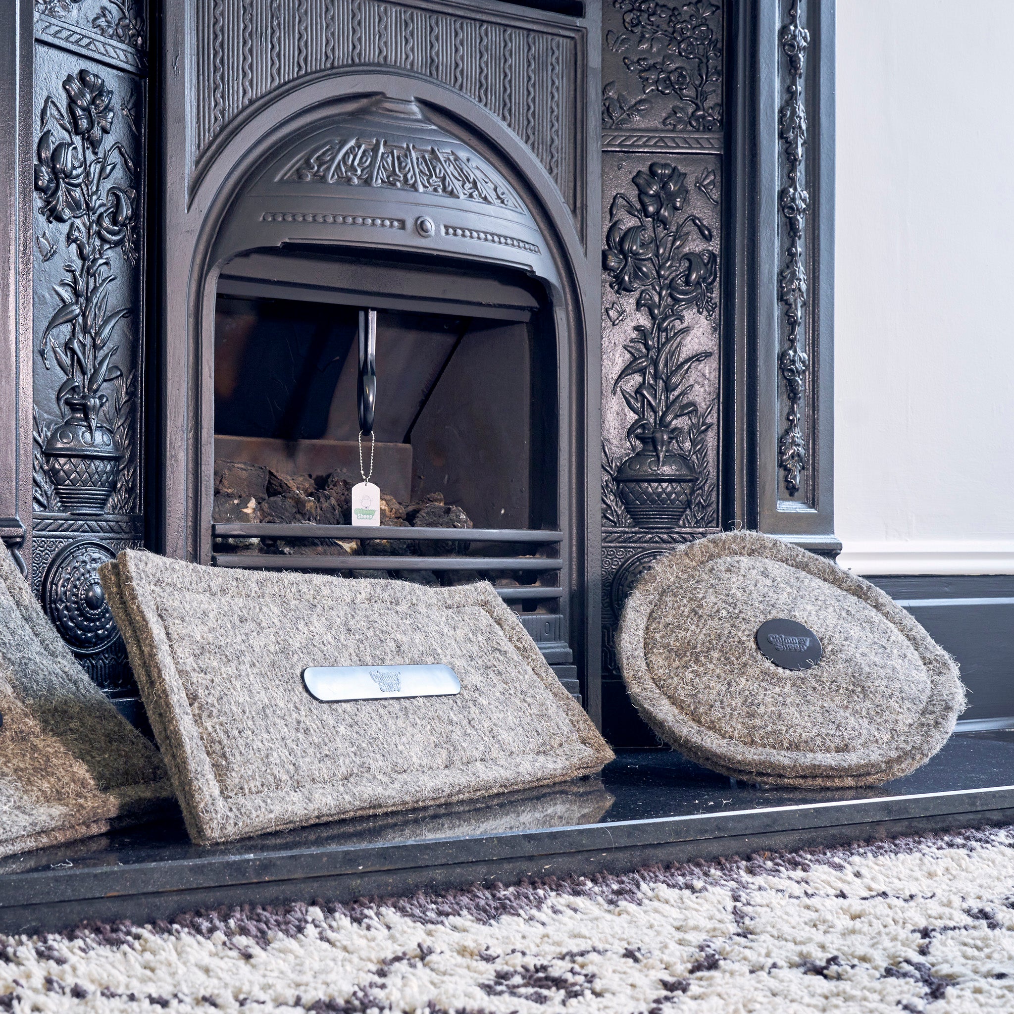 Two Chimney Sheep draught excluders in front of a fireplace.