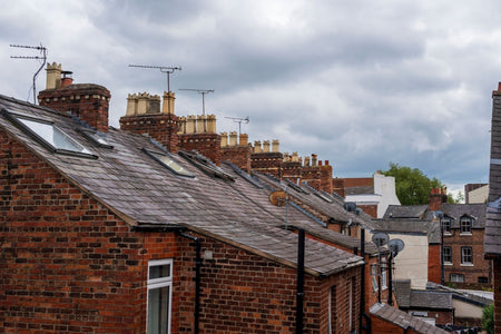 Terraced row of houses some with blocked off chimneys but most with several chimney pots per property