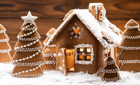 Gingerbread House illuminated from the inside with gingerbread Christmas trees on icing snow