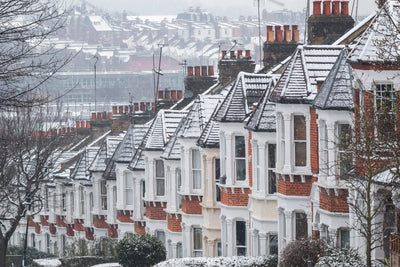 terraced row of houses in winter snow, each with four pots per chimney stack, illustrating how many open chimneys there are in the UK