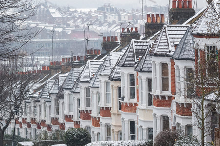 terraced row of houses in winter snow, each with four pots per chimney stack, illustrating how many open chimneys there are in the UK