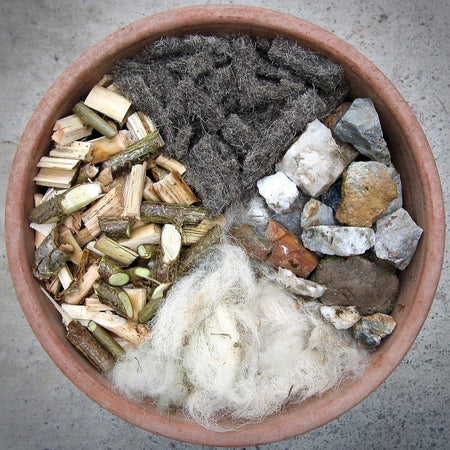 A Plant pot containing Chimney Sheeps felt shillies along with tree bark sheeps wool and rocks