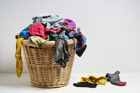 A washing basket containing a load of dirty laundry of multiple colours