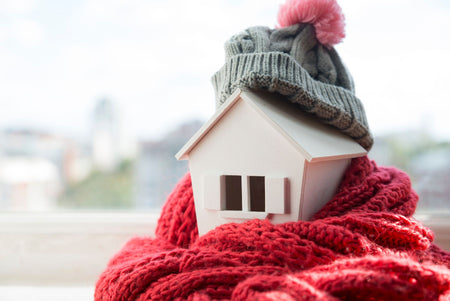 sheep wool insulation illustrated by a model of a house wrapped in a cosy red scarf and grey bobble hat