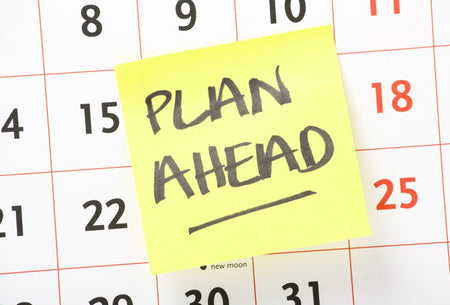 A calendar with the sticky note ' plan ahead' stuck on to it