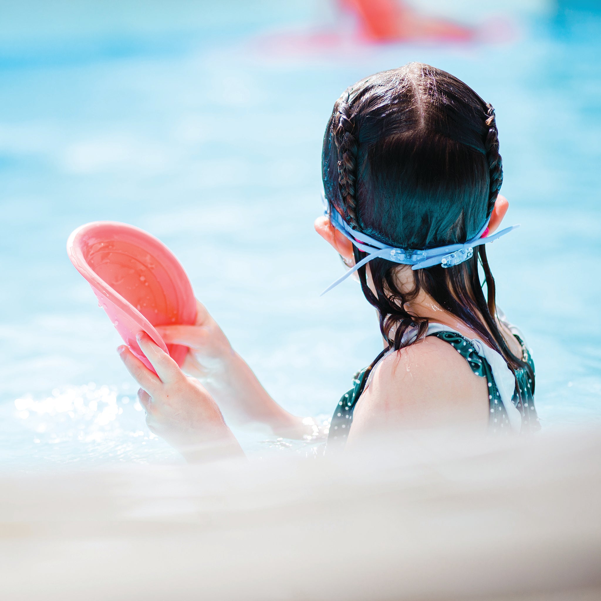child in pool with plastic free frisbee