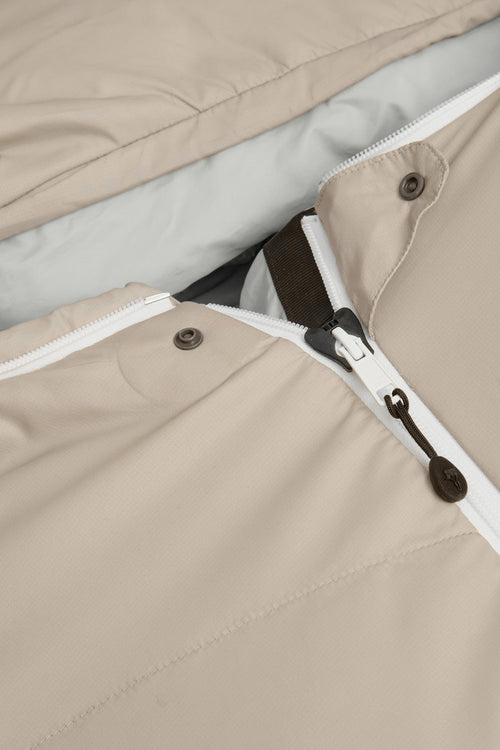 A beige mummy-style sleeping bag with a white zipper and small red logo details, shown against a plain white background.
