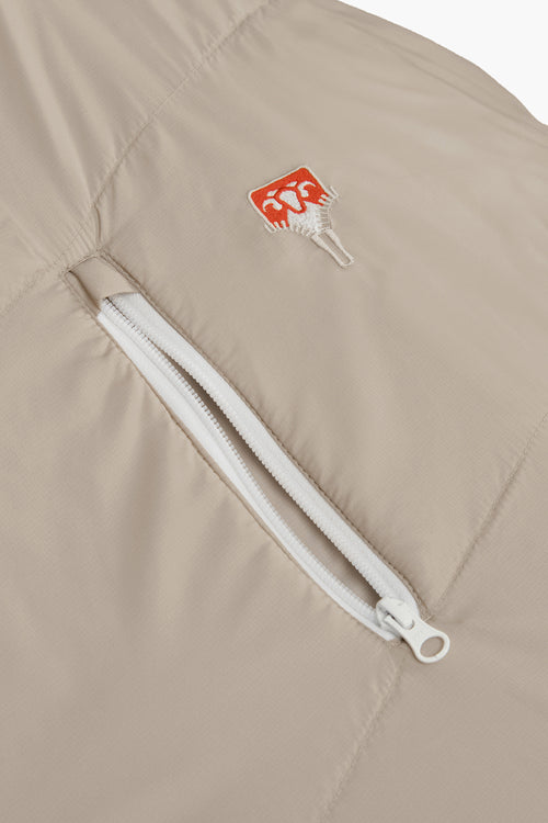 A beige mummy-style sleeping bag with a white zipper and small red logo details, shown against a plain white background.