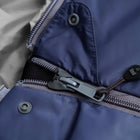Close-up detail of a navy blue sleeping bag showing a grey zipper, zipper pull, snap button, and a light grey inner lining.
