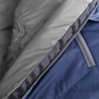 Close-up of a wool sleeping bag showing a light grey quilted inner panel folded over a blue outer shell with a grey zipper.