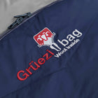 Close-up of a navy blue Grüezi bag with a silver zipper, showing the embroidered red and white Grüezi Wool Inside logo.