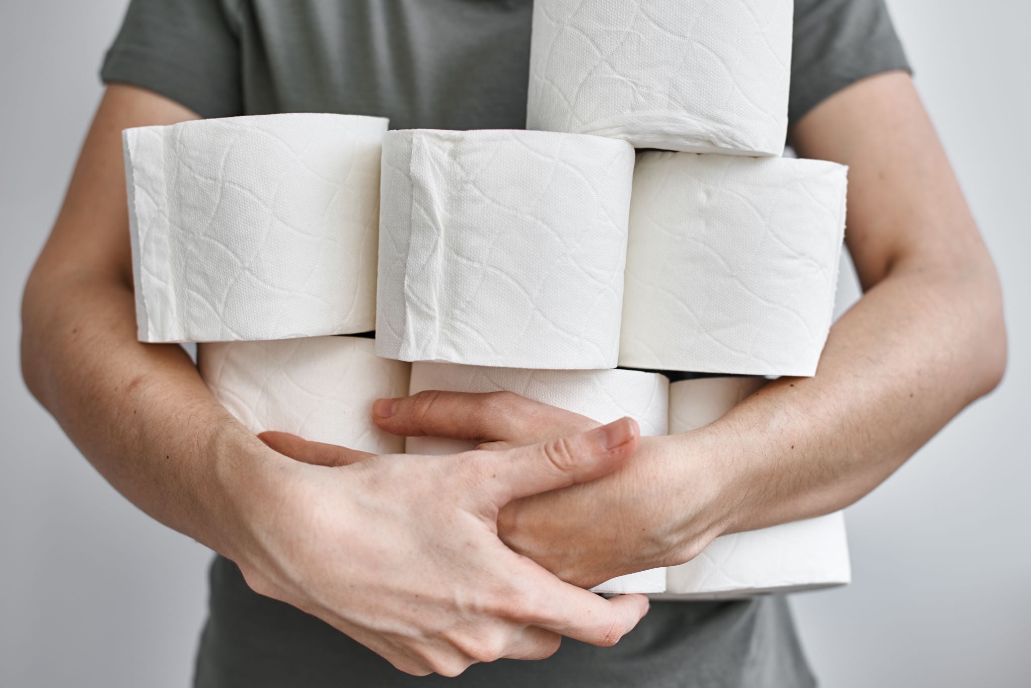 Man holding 7 rolls of toilet paper made of 100% recycled materials 