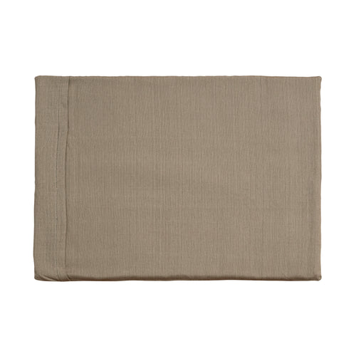 A black and white border collie sits upon a Chimney Sheep Luzury wool dog bed in the grey and white floral pattern. The wool dog bed sits upon some grass as the collie looks to the left with erect ears.