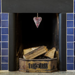 Namaste brown floral metal heart dangle hanging above logs in a fireplace. thumbnail