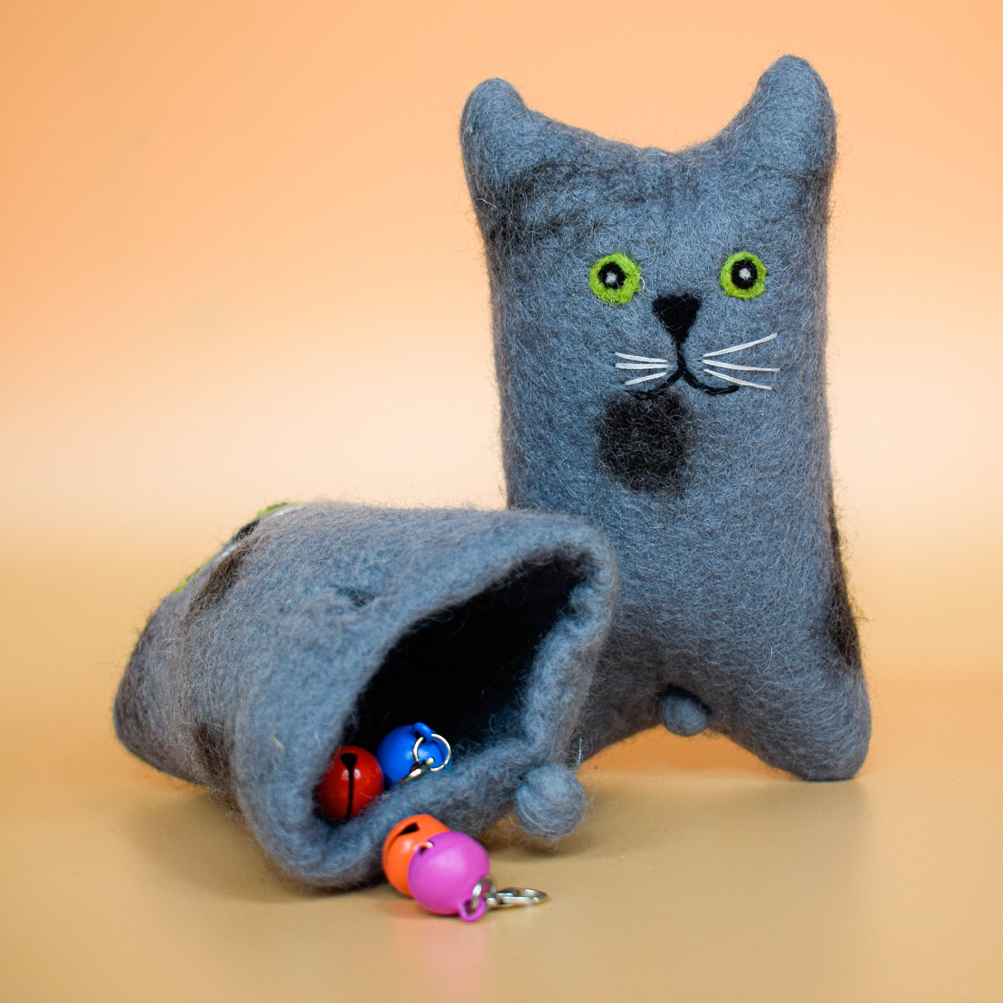 A blue hoomans friends felted wool natural cat toy placed on an orange background