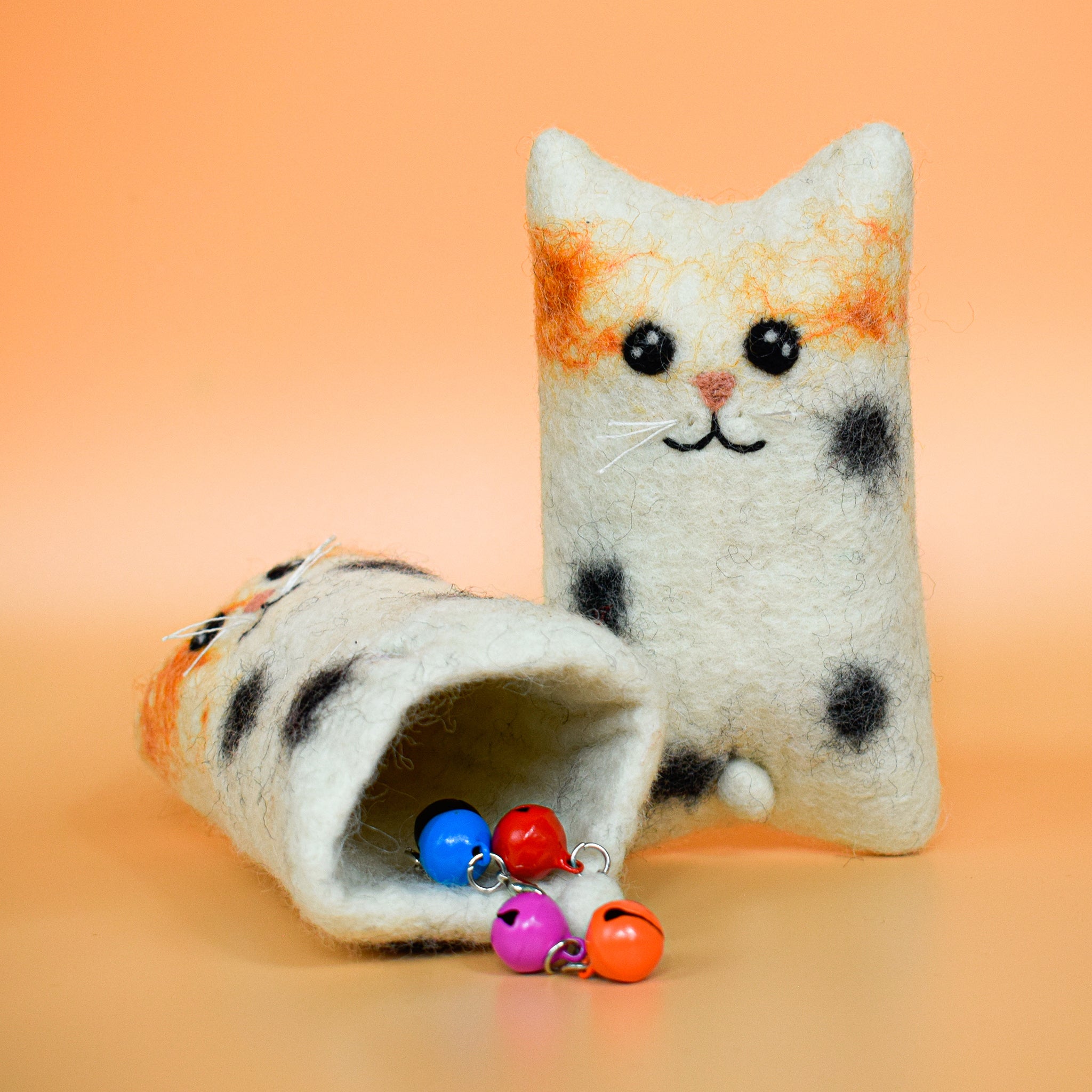 A white hoomans friends felted wool natural cat toy placed on an orange background