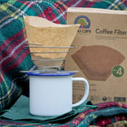 portable wire coffee dripper with coffee filter paper and enamel mug and tartan picnic rug