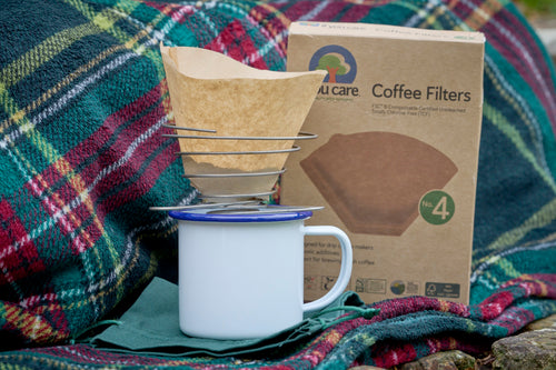 portable wire coffee dripper with coffee filter paper and enamel mug and tartan picnic rug
