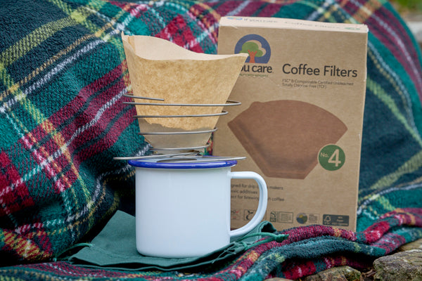 portable wire coffee dripper with coffee filter paper and enamel mug and tartan picnic rug