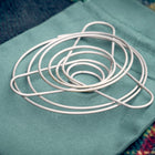 Portable wire coffee dripper collapsed flat, on top of green organic cotton carry pouch