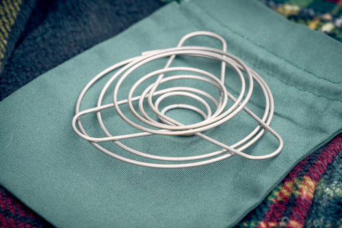 portable wire coffee dripper with coffee filter paper and enamel mug and tartan picnic rug