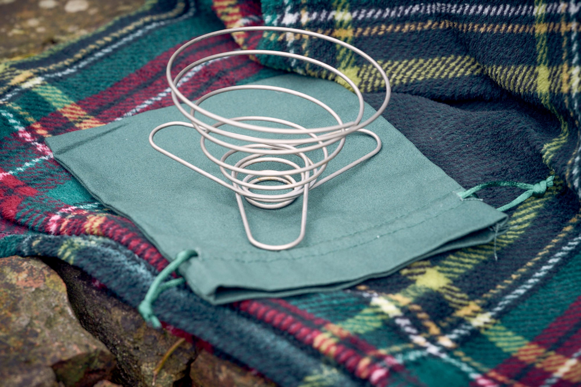 Portable wire coffee dripper on top of green organic cotton carry pouch