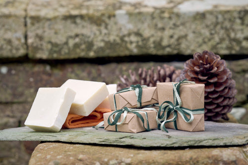 Stack of three Olive Oil Castile soaps stacked on an orange flannel on top of a navy blue and white striped towel