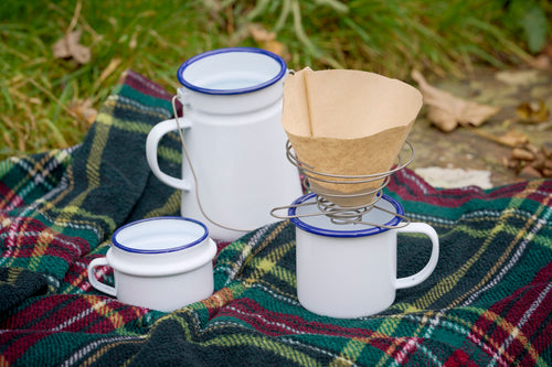 portable wire coffee dripper with coffee filter paper and enamel mug and tartan picnic rug