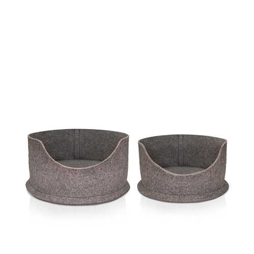 A white cat with yellow eyes, sitting inside a Chimney Sheep PteSnug wool felt cat bed. The bed is sitting on a wooden floor. There is a yellow wool filled cushion inside the bed.