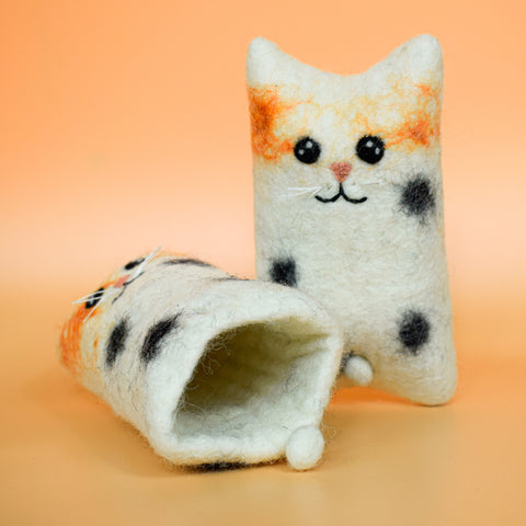 A hoomans friends felted wool natural cat toy placed on an orange background