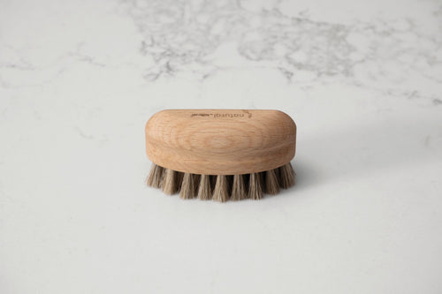 Wooden nailbrush with bristles on a marble background