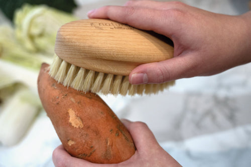 FSC and natural bristle vegetable scrubbing brush on marble background
