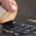 Person cleaning a laptop keyboard with a brush