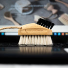 Hillbrush laptop brush on a laptop keyboard with a blurred background of cleaning tools.
