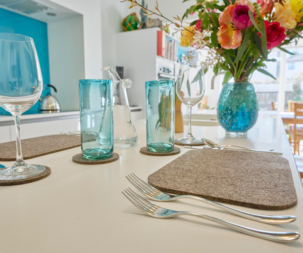 Table made for a meal with grey felt tablemats and coasters