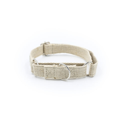 A natural jute hemp martingale style dog collar. The collar is made of woven hemp. The collar is stood on a white background with the two silver metal buckles and silver metal ring visible