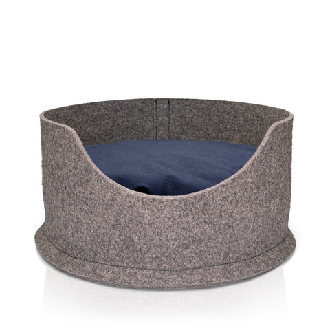 A blue roan cocker spaniel lying comfortably in a sustainable, grey wool felted high side round dog bed. The bed also has a yellow cushion in it which is also filled with sheep's wool.
