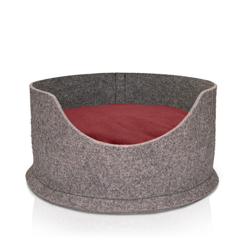 A blue roan cocker spaniel lying comfortably in a sustainable, grey wool felted high side round dog bed. The bed also has a yellow cushion in it which is also filled with sheep's wool.
