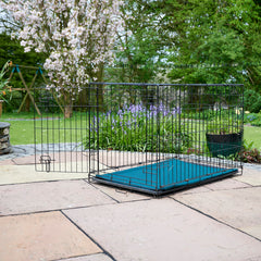 Black, metal dog crate, with a green eco-friendly handmade, wool filled crate liner inside. The crate is placed on a patio. thumbnail