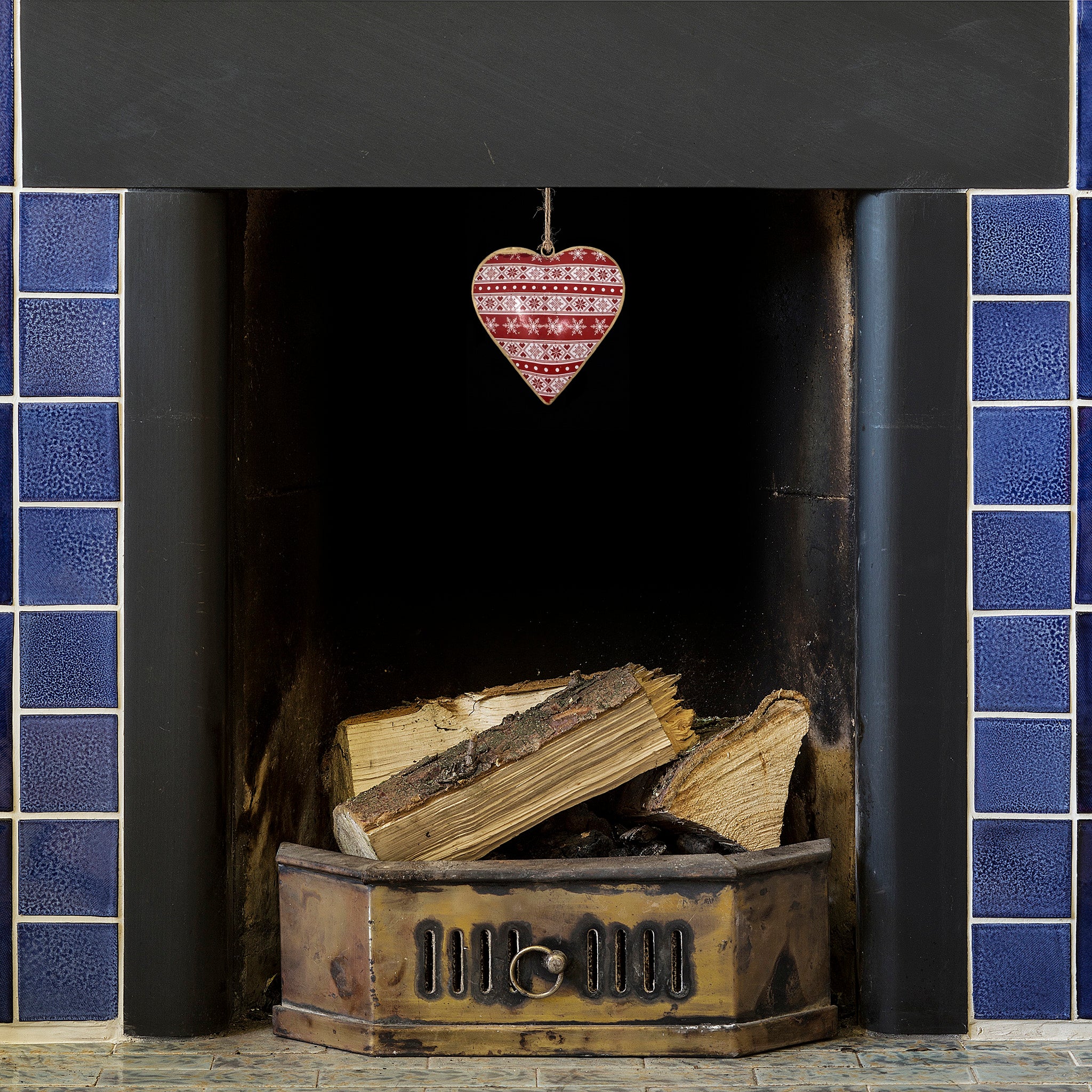 A nordic heart painted dangle in a blue tile fireplace. Includes a winter inspired design.