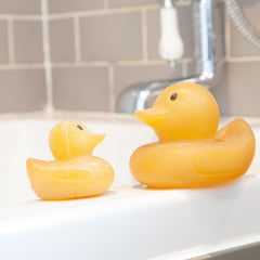 Large and small natural rubber duck sitting on side of bathtub.  thumbnail