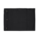 A Chimney Sheep wool filled portable rollup travel dog bed sits on a white background. This flat rectangular portable roll up dog bed is in the colour black. You can see the white poppers which allow it to be simply rolled into a tight package for easy transportation.