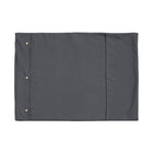 A Chimney Sheep wool filled portable rollup travel dog bed sits on a white background. This flat rectangular portable roll up dog bed is in the colour grey. You can see the white poppers which allow it to be simply rolled into a tight package for easy transportation.