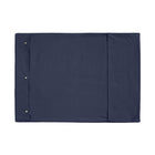 A Chimney Sheep wool filled portable rollup travel dog bed sits on a white background. This flat rectangular portable roll up dog bed is in the colour blue. You can see the white poppers which allow it to be simply rolled into a tight package for easy transportation.