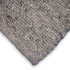 Close-up of a textured woven rug corner showing Herdwick and Texel shades of grey on a white background.