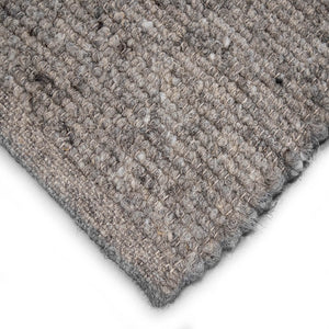 Close-up of a textured woven rug corner showing Herdwick and Texel shades of grey on a white background.